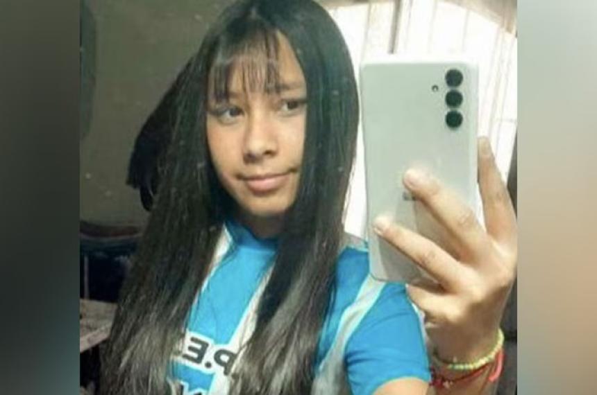 Una joven posa para un selfie mostrando su cabello largo y una camiseta azul con rayas blancas mientras sostiene un teléfono móvil
