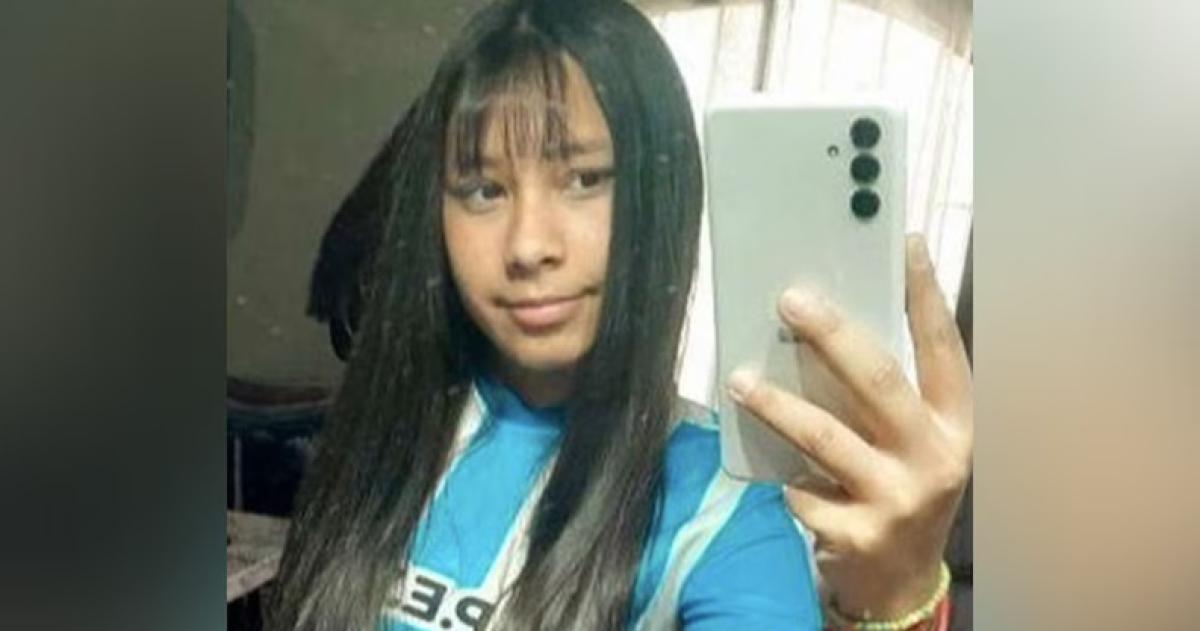 Una joven posa para un selfie mostrando su cabello largo y una camiseta azul con rayas blancas mientras sostiene un teléfono móvil
