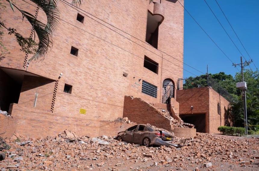 Un edificio dañado y un vehículo cubierto de escombros en Cali Colombia